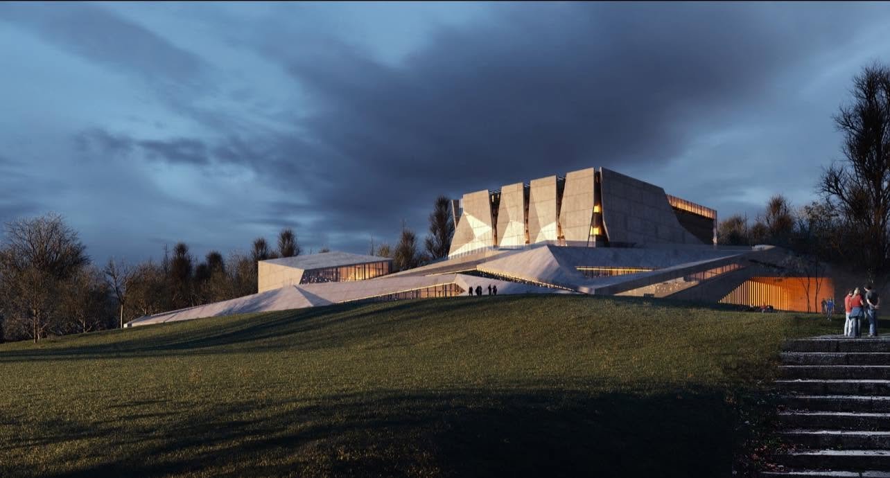 Dusk rendering of the Vilnius Concert Hall proposal with angular roof planes, a faceted central hall and illuminated glazing within a sloping landscape.