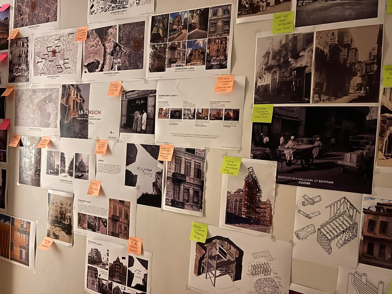 Angled view of the La Pension project wall combining city maps, architectural photographs, concept sheets, drawings and colored sticky notes.