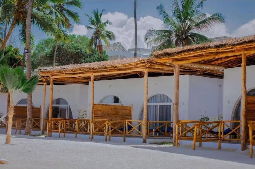Royal Mandrine Resort site photograph of white arched room fronts with timber-post verandas, thatched roofing, and palms.