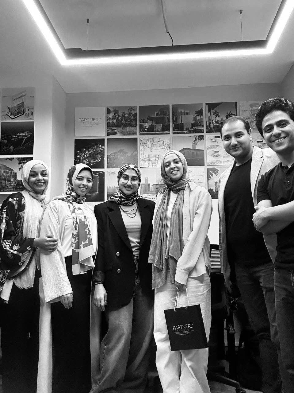 Black-and-white group photograph of six people inside the Partnerz office, with architectural presentation sheets on the wall.