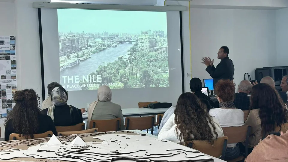 Ahmed Batea presenting to an architecture audience beside a projected image of the Nile.